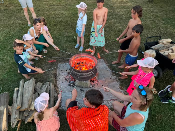 Kinder und Eltern grillen am Lagerfeuer